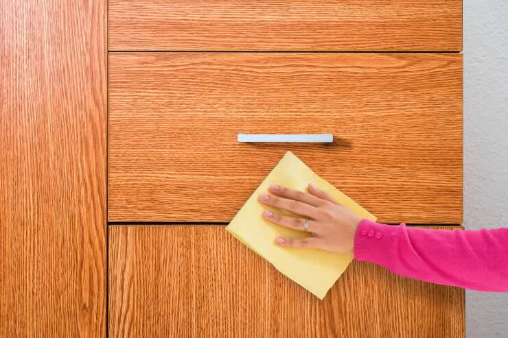 mano che pulisce mobile legno
