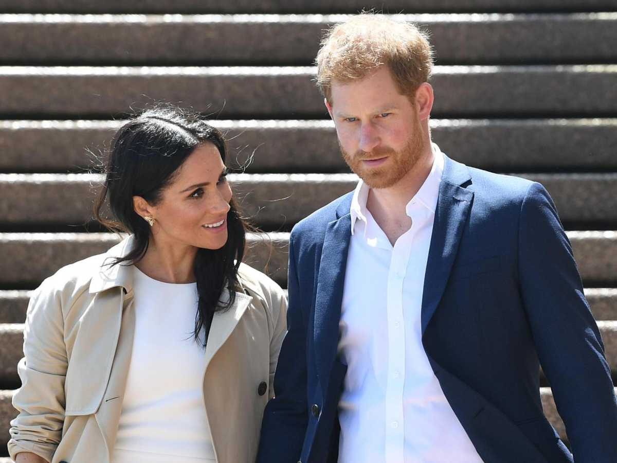Harry e Meghan scendono le scale, Meghan sorride a Harry