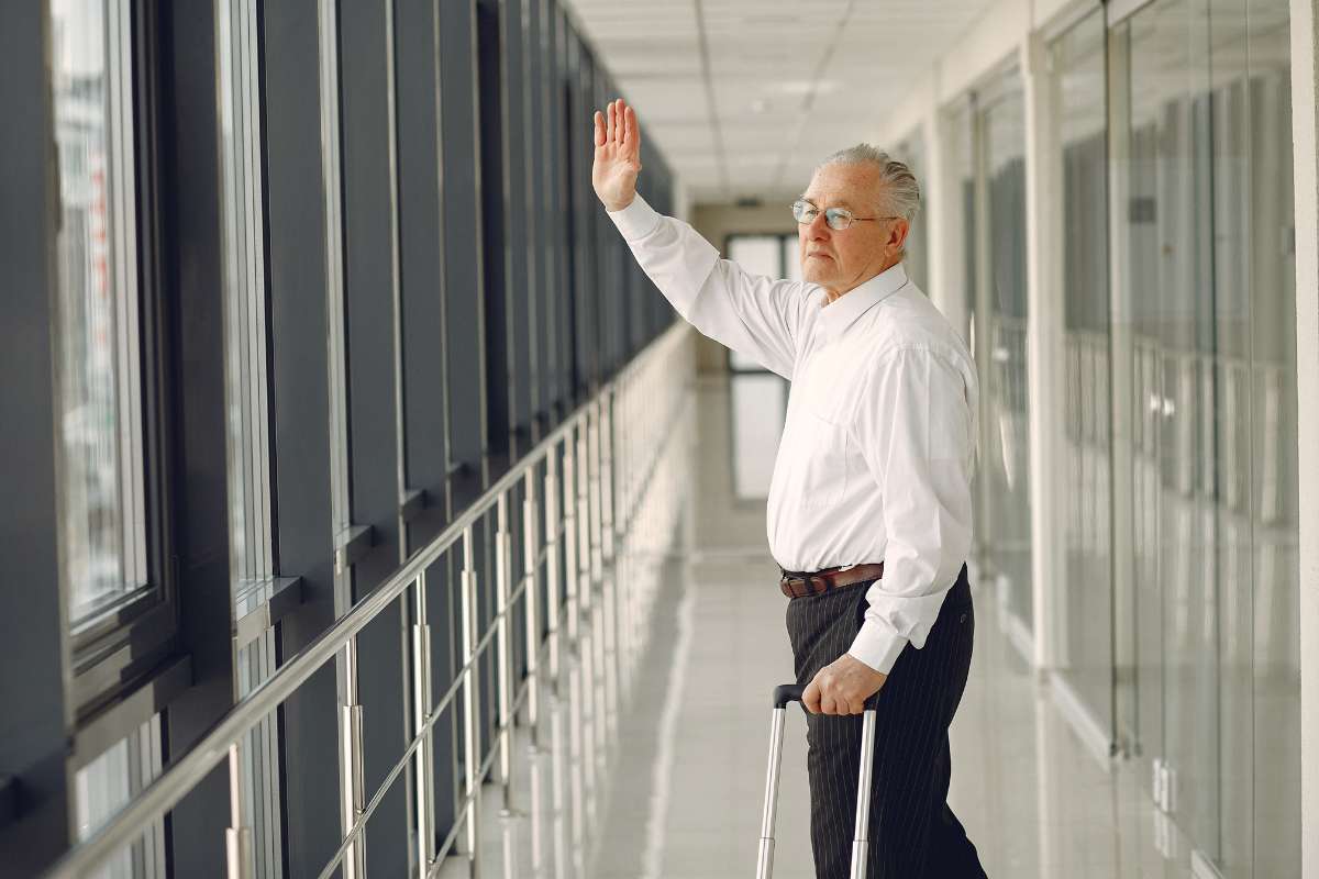 uomo con deambulatore saluta con la mano